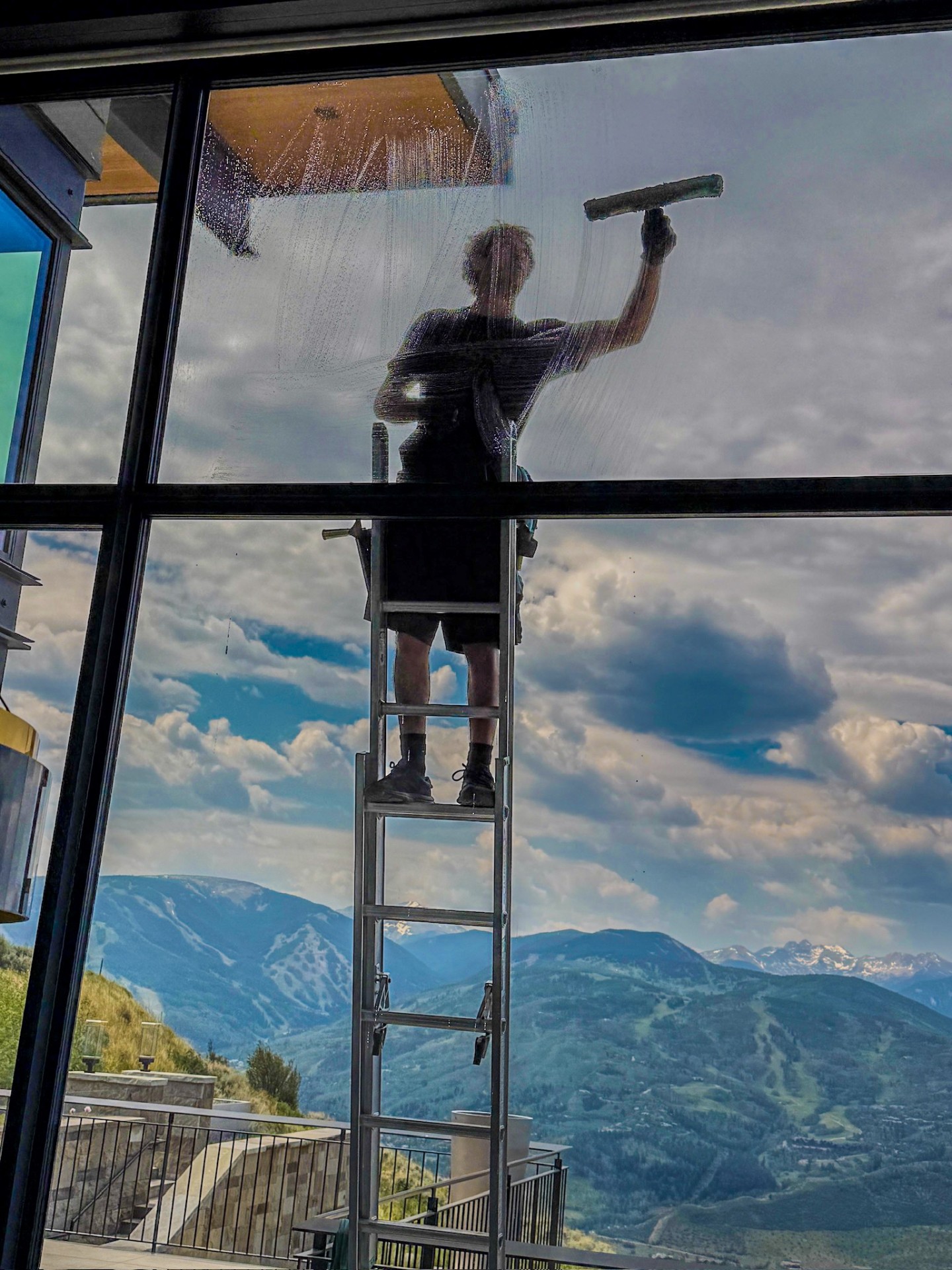 Residential window cleaning on a tall window at a custom mountain home at Mountain Star in Avon, Colorado with the Vail Valley behind