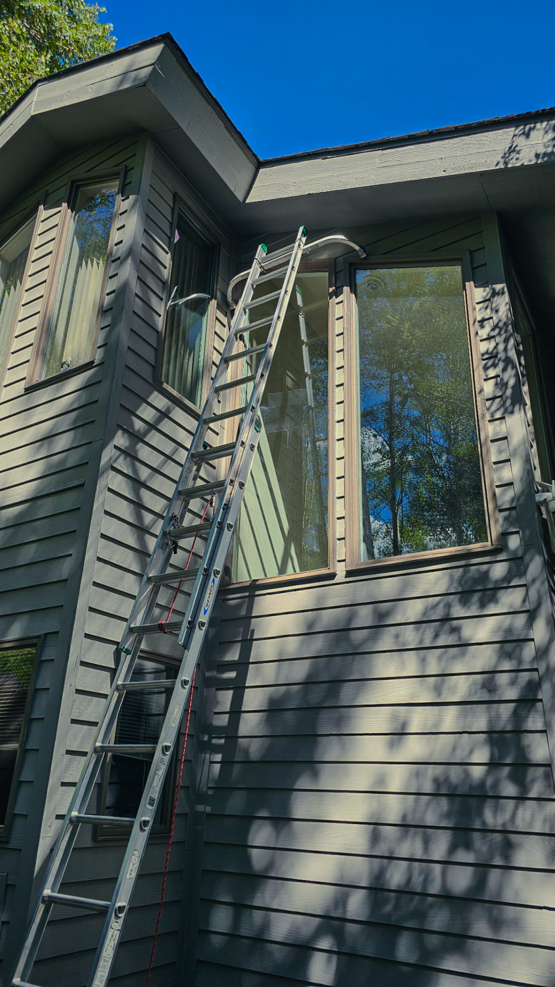 Residential window cleaning on a green wood-sided home with second-story windows in Singletree, Edwards, Colorado