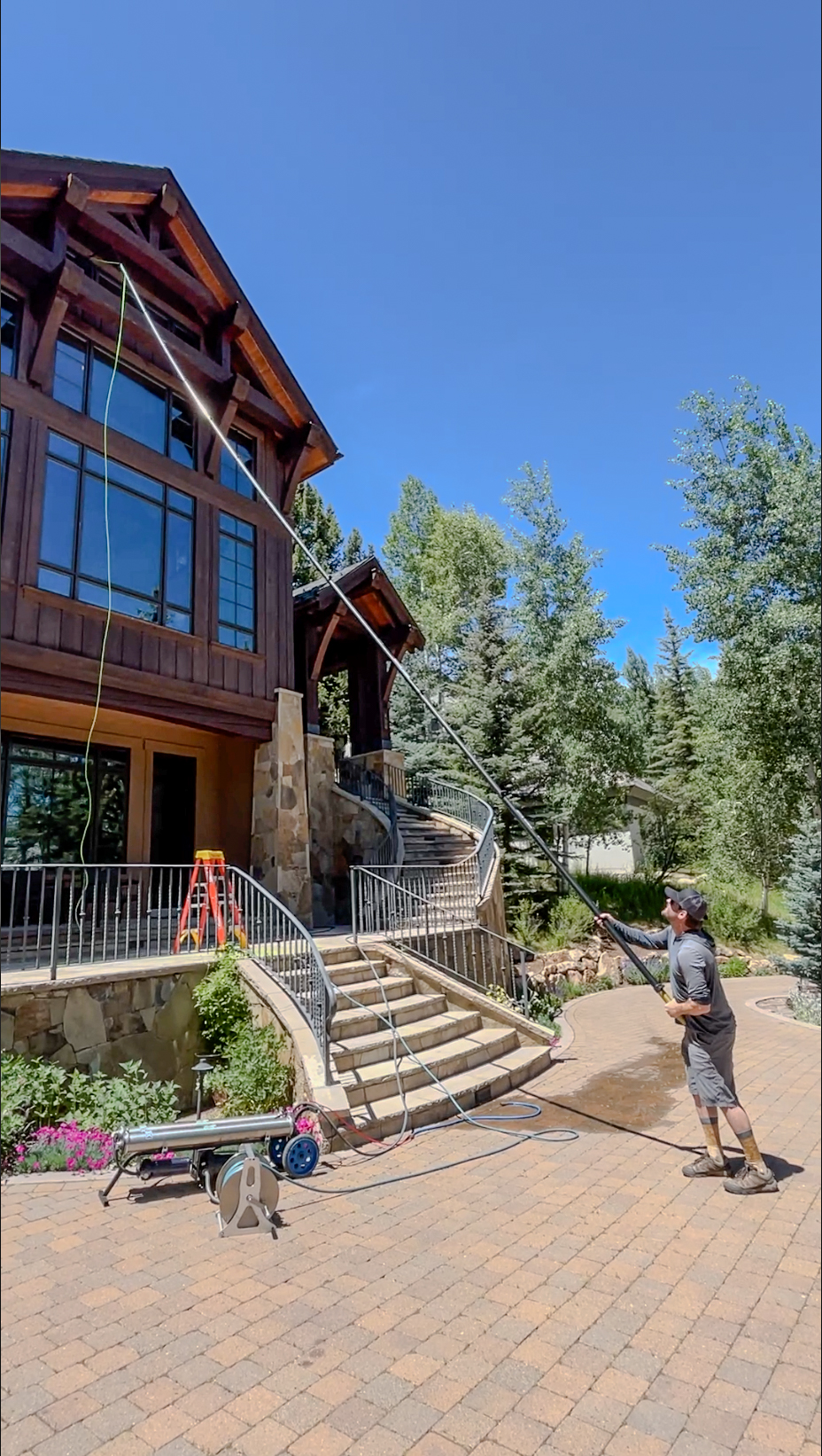 Residential window cleaning on tall second-story windows of a timber and stone mountain home in Beaver Creek, Colorado