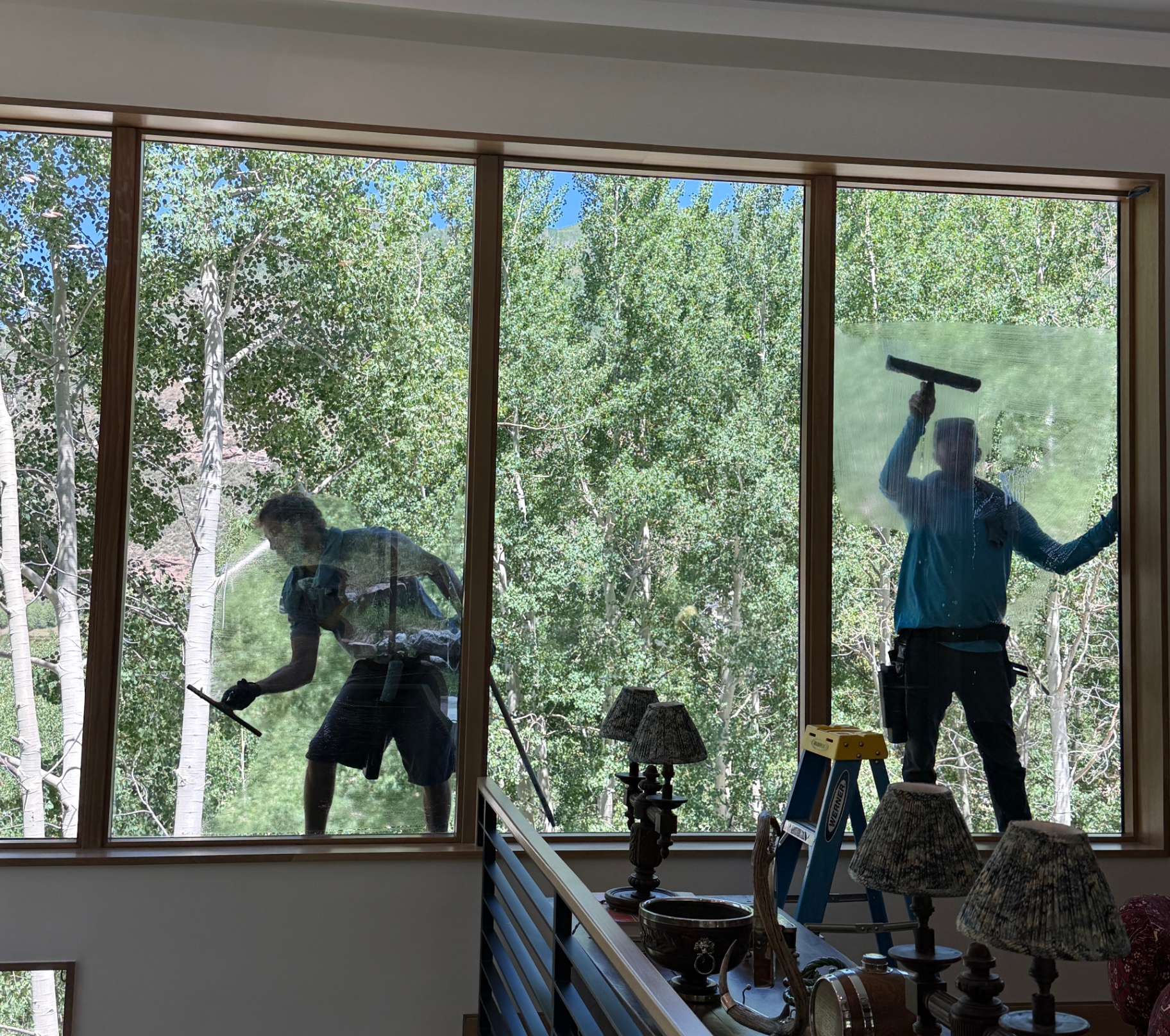 Clean Up Group technicians squeegeeing tall aspen-view windows on a Vail Valley home
