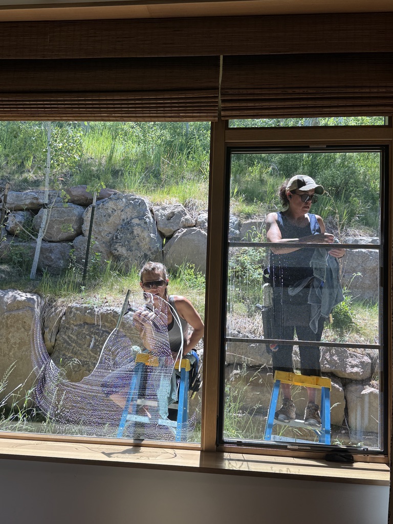 Clean Up Group crew cleaning interior glass at a Vail Valley home, seen from inside